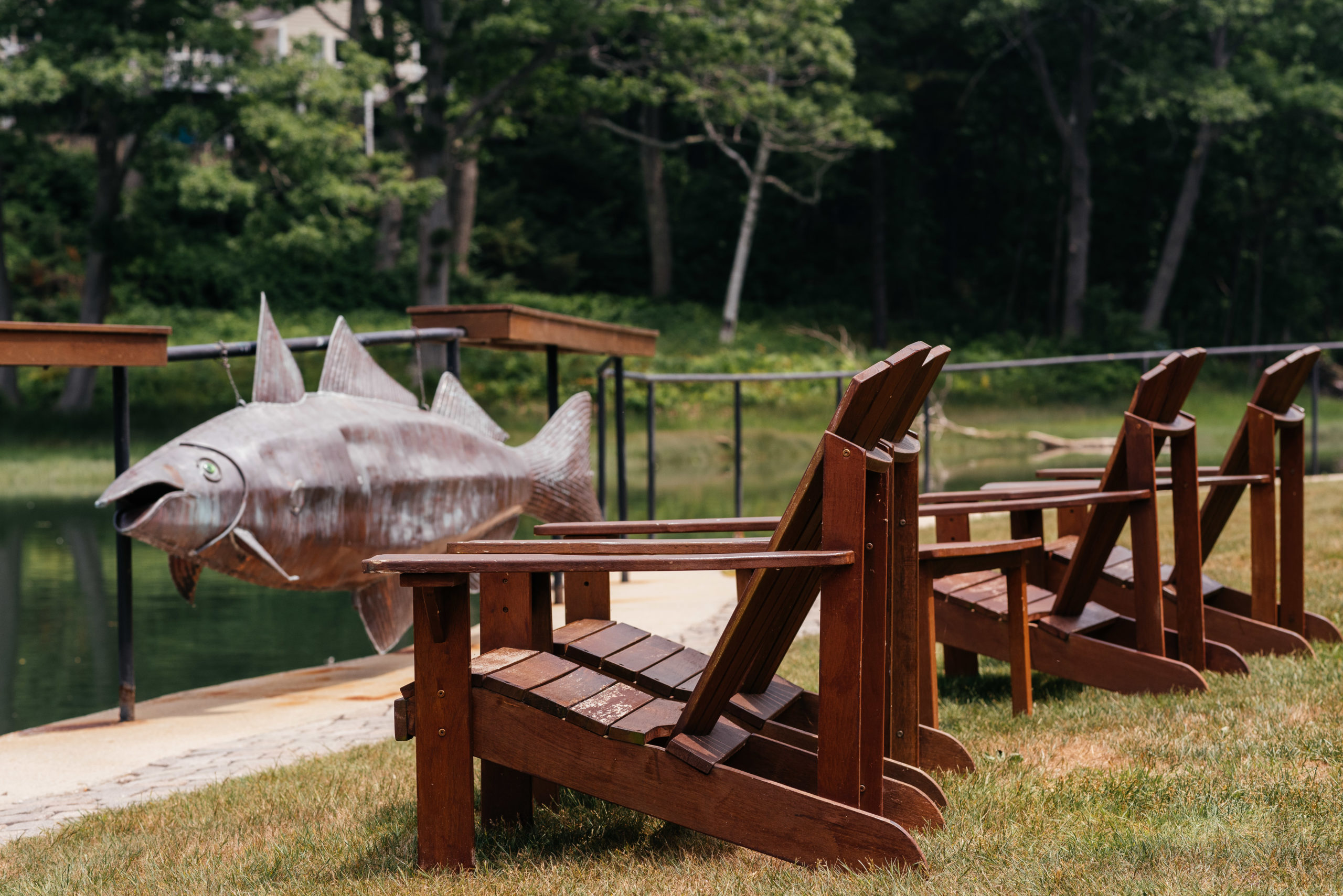 adirondack chairs and metal fish hanging on fence